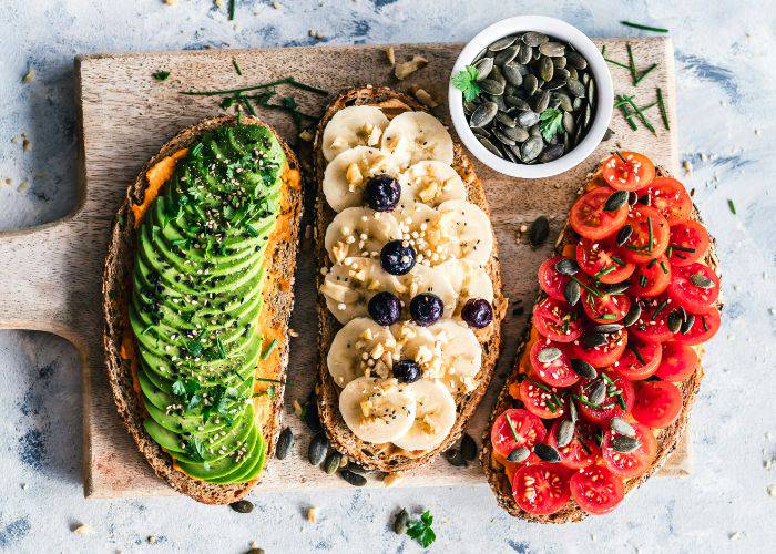 Three vegan breakfast toasts: avocado, banana and cherry tomatoes.